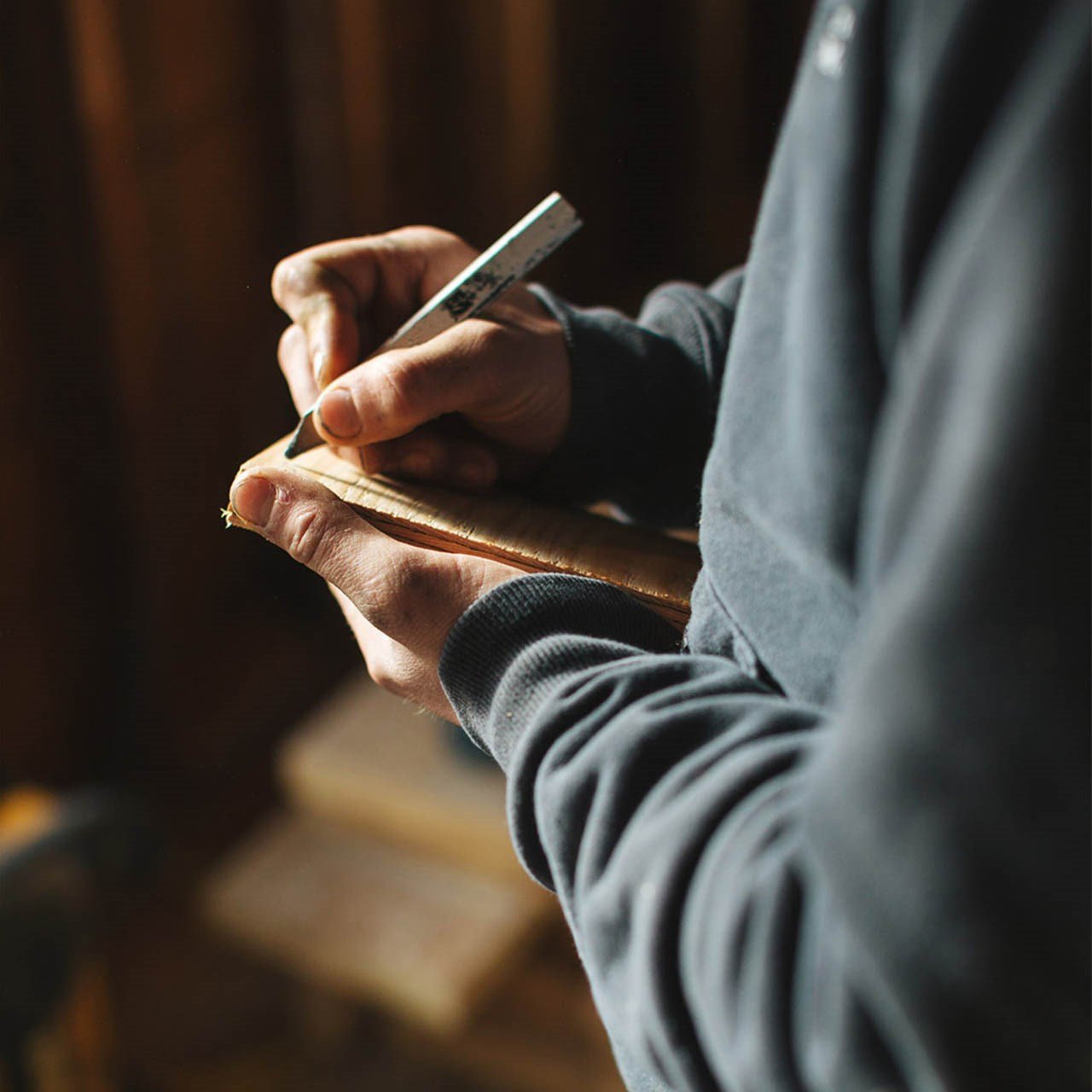 Photo de deux mains d'ouvrier tenant un crayon et un carnet. Il prend des notes sur un chantier de construction.