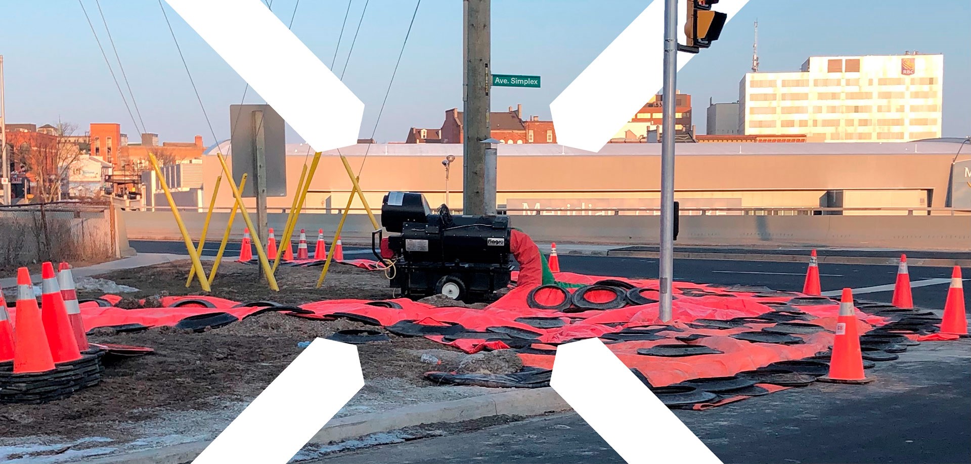 Photo en extérieur sur un chantier avec une chaufferette à flammes sur roues avec des tuyaux non gonflés au sol. 