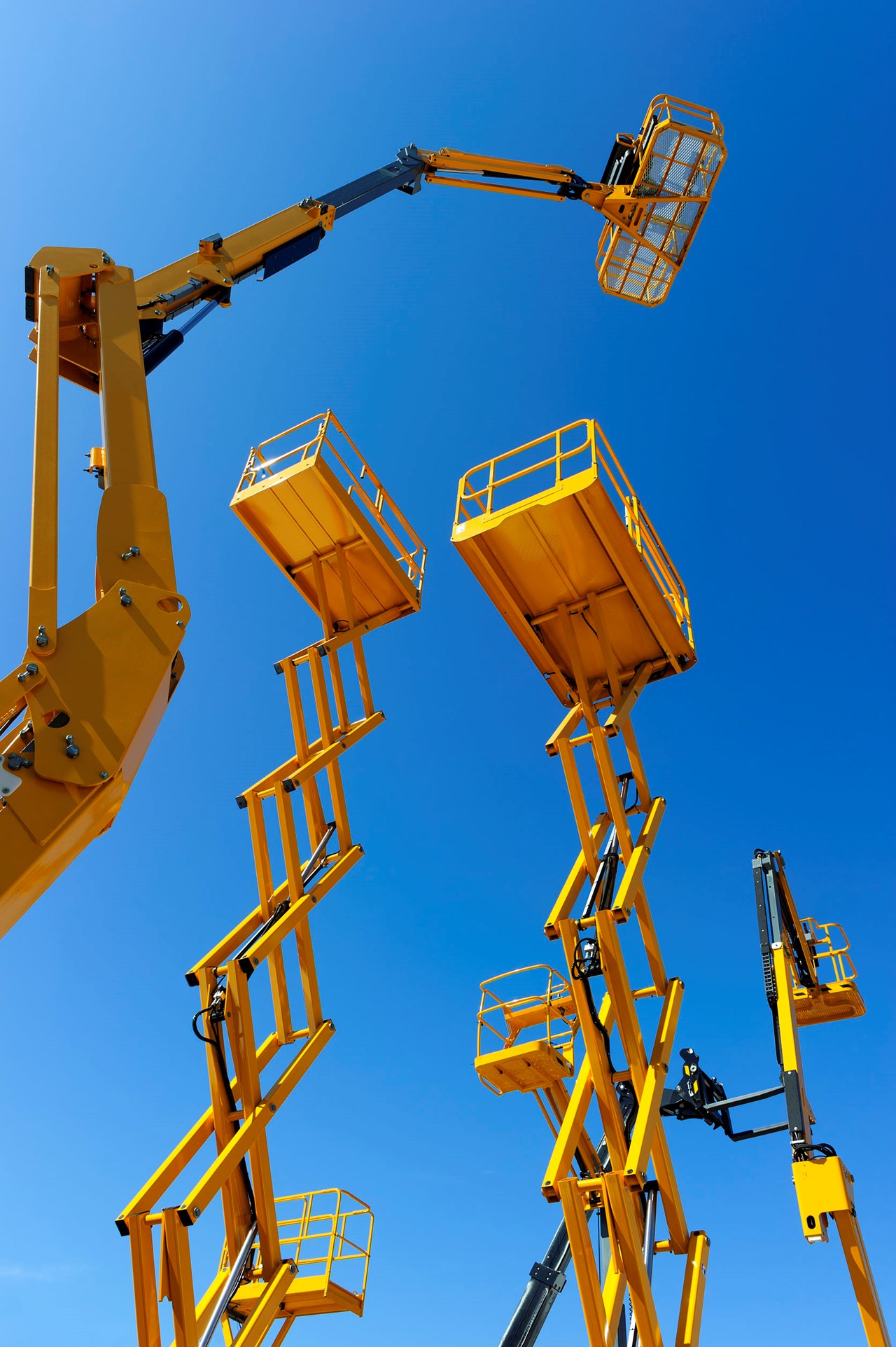 Nacelles articulées et plateformes élévatrices jaunes déployées en hauteur sur fond de ciel bleu, pour le travail en hauteur
